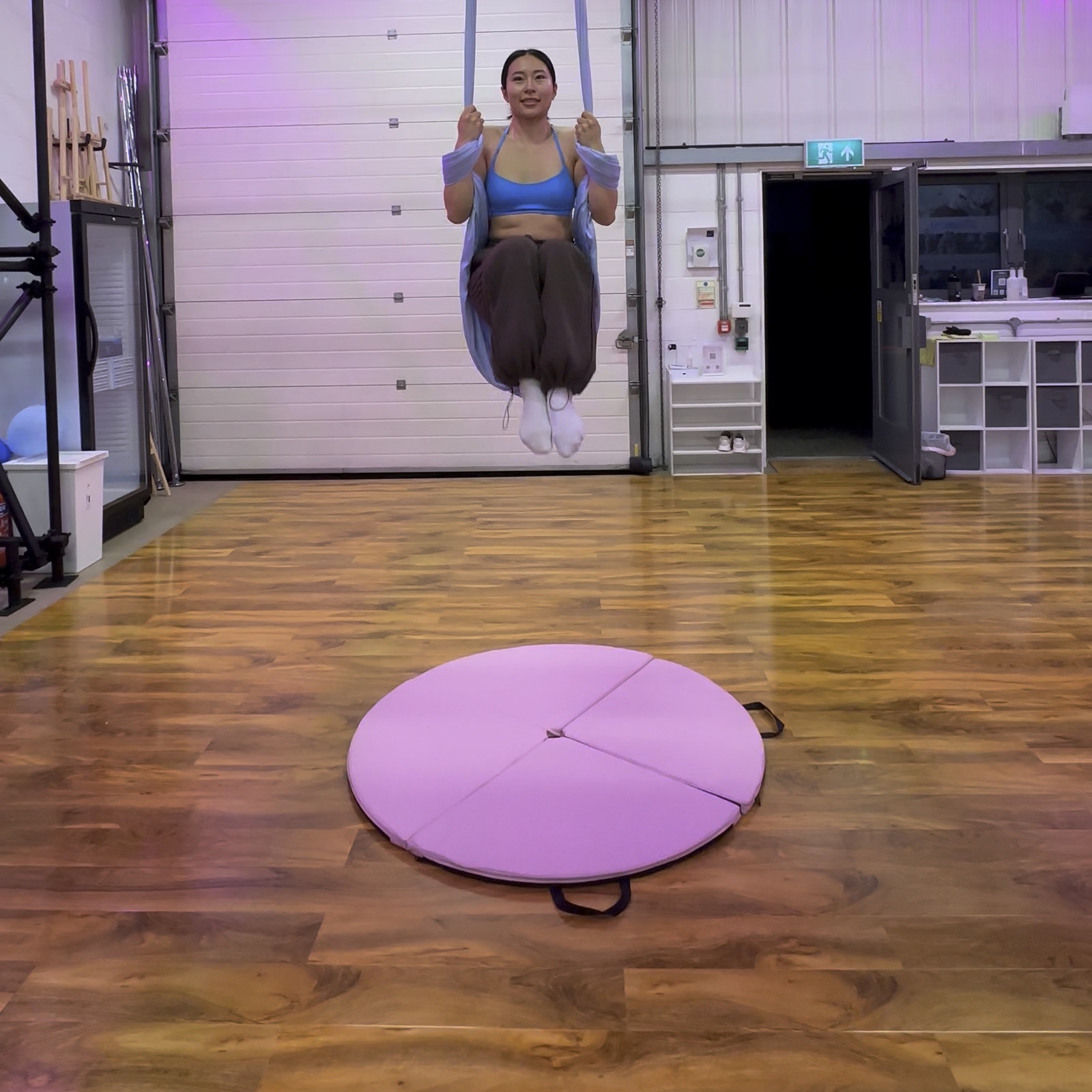 A student smiling during a suspended knee tuck with the aerial hammock