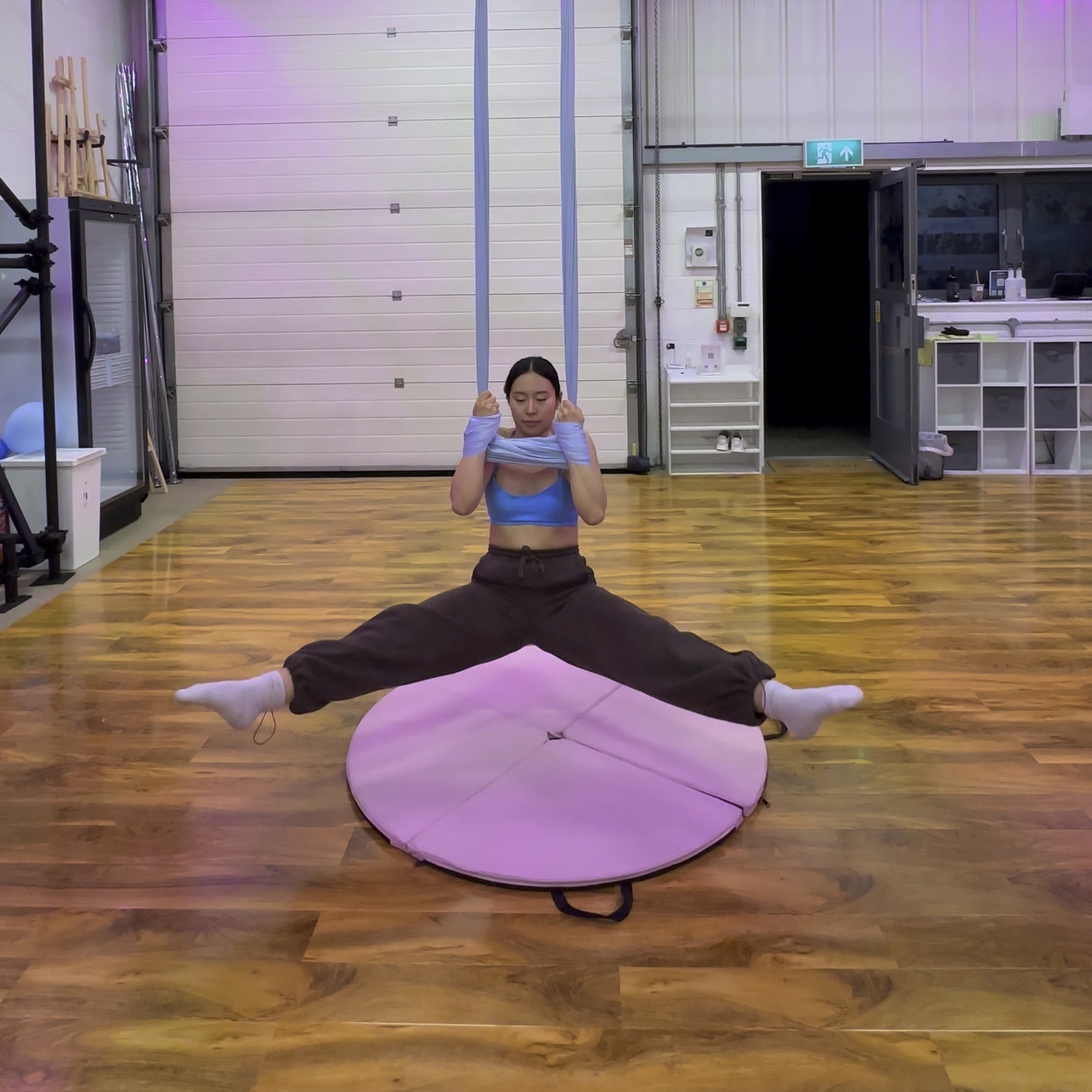 A student stretching with legs wide while supported by the hammock