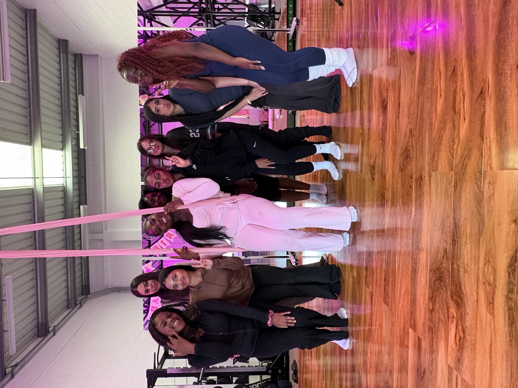 A birthday group posing together beside pink aerial silks
